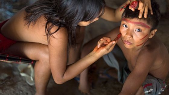 Ein Yanomami-Mädchen aus Watoriki, Brasilien, schmückt die Gesichter ihrer Geschwister mit der typischen Yanomami-Bemalung. Foto: Adveniat/Escher.