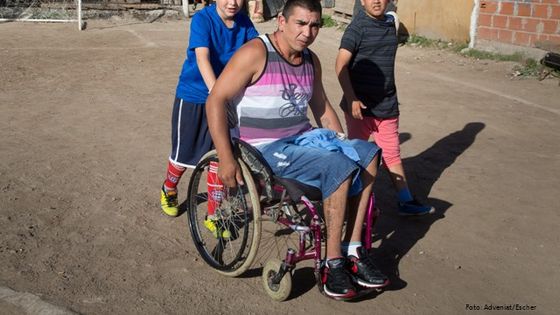 In einem Armenviertel von Buenos Aires schieben die Söhne ihren gehbehinderten Vater zum Sportplatz. Foto: Adveniat/Escher