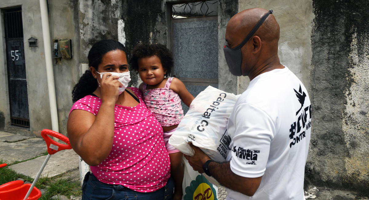 Ein CUFA-Helfer verteilt während der Pandemie Lebensmittel an eine Favela-Bewohnerin. Foto: Tobias Käufer