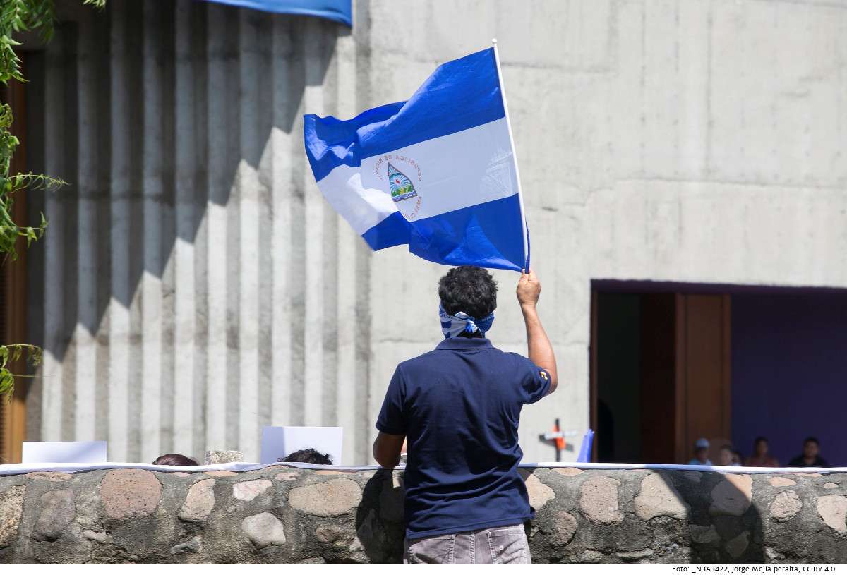 Ein Mann schwenkt vor der Kathedrale in Nicaraguas Hauptstadt Managua die Nationalflagge zum Gedenken an die Opfer, die bei den Protesten gegen das Ortega-Regime im April 2018 getötet wurden. Foto: _N3A3422, Jorge Mejía peralta, CC BY 4.0