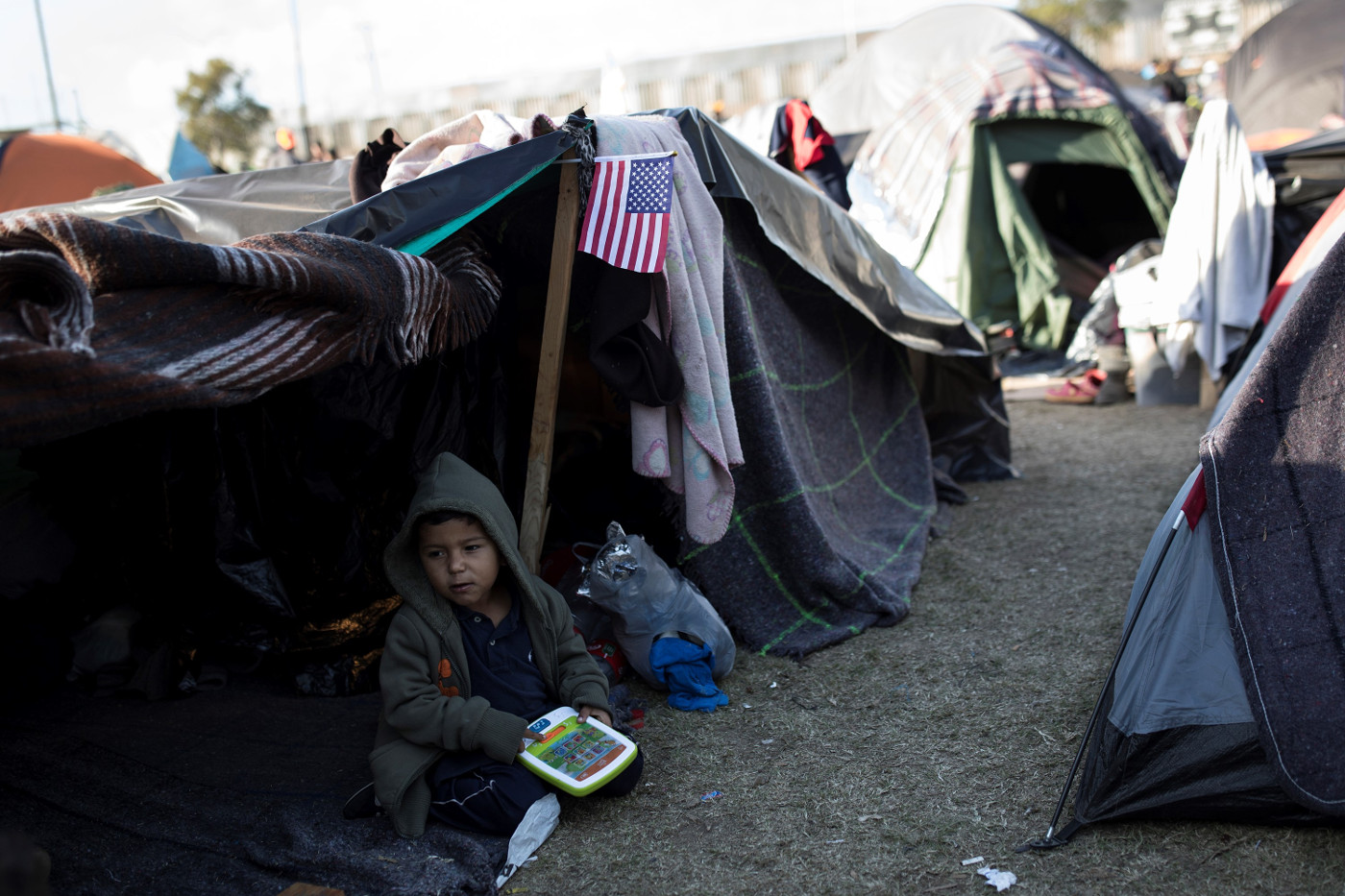 Notunterkunft auf dem Benito Juárez-Sportfeld in Tijuana, Mexiko. Der dreijährige Liam spielt vor seinem Zelt, ungefähr 100 Meter von der US-Grenze entfernt. Foto (2018): Adveniat/Hans-Máximo Musielik